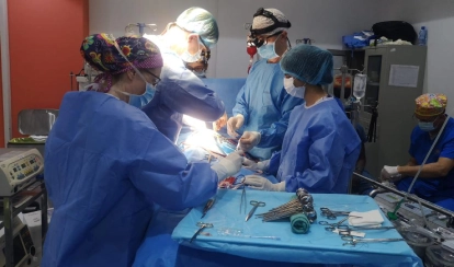 A group of students and staff members of BERNOSSUS pose together for a photo outside the entrance to the community health centre.