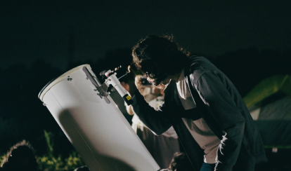 A student looks through a telescope.