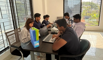 Students sitting around a table working on their laptops.
