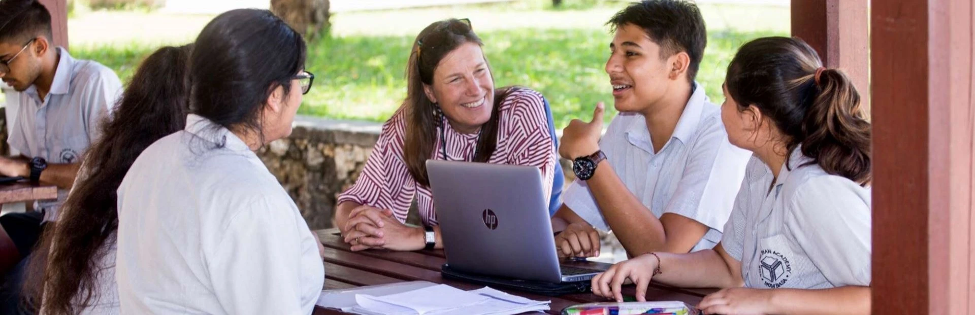 Students and a staff member having a discussion outdoors.