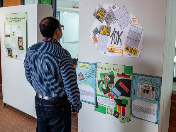 A student presents their theory of knowledge exhibition display to a visitor, discussing ideas about knowledge and understanding.