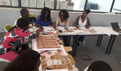A group of educators and professionals stand in front of a government primary school during a PDC field visit for the KIX project observation.