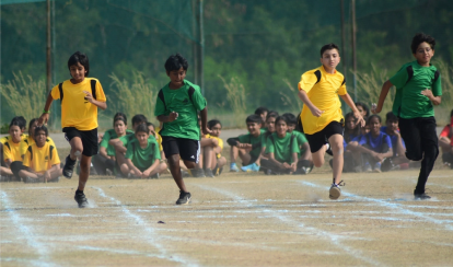 Students running on a field for a track and field event.