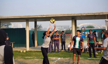 Students play volleyball on the outdoor court.