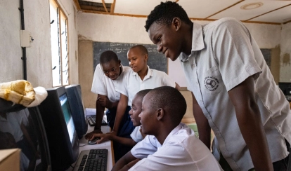 An Academy student teaching computer skills to students in his hometown