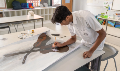 A student paints a realistic image of two guitars on a large canvas